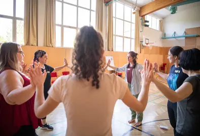 Teilnehmende stehen im Kreis und halten sich an den Händen.