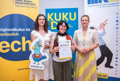 Teilnehmende Person und Vortragende posieren mit Zertifikat.