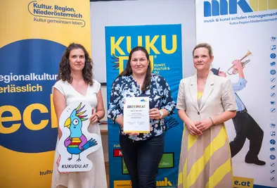 Teilnehmende Person und Vortragende posieren mit Zertifikat.