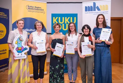 Teilnehmende Person posieren mit Zertifikat und KUKUDU Logo.