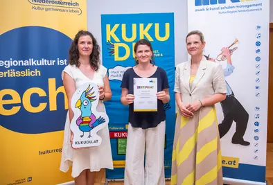 Teilnehmende Person und Vortragende posieren mit Zertifikat.