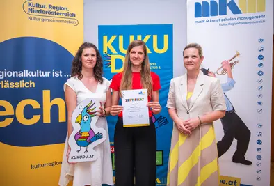 Teilnehmende Person und Vortragende posieren mit Zertifikat.