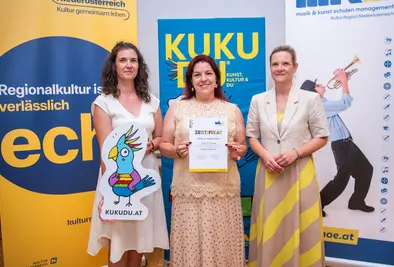 Teilnehmende Person und Vortragende posieren mit Zertifikat.