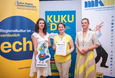 Teilnehmende Person und Vortragende posieren mit Zertifikat.