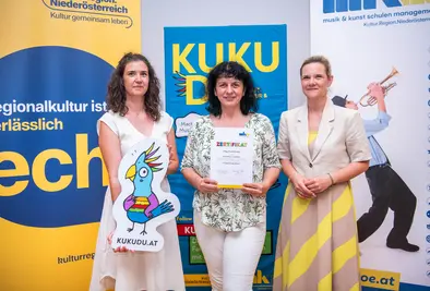 Teilnehmende Person und Vortragende posieren mit Zertifikat.