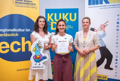 Teilnehmende Person und Vortragende posieren mit Zertifikat.