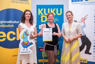 Teilnehmende Person und Vortragende posieren mit Zertifikat.