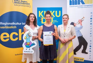 Teilnehmende Person und Vortragende posieren mit Zertifikat.